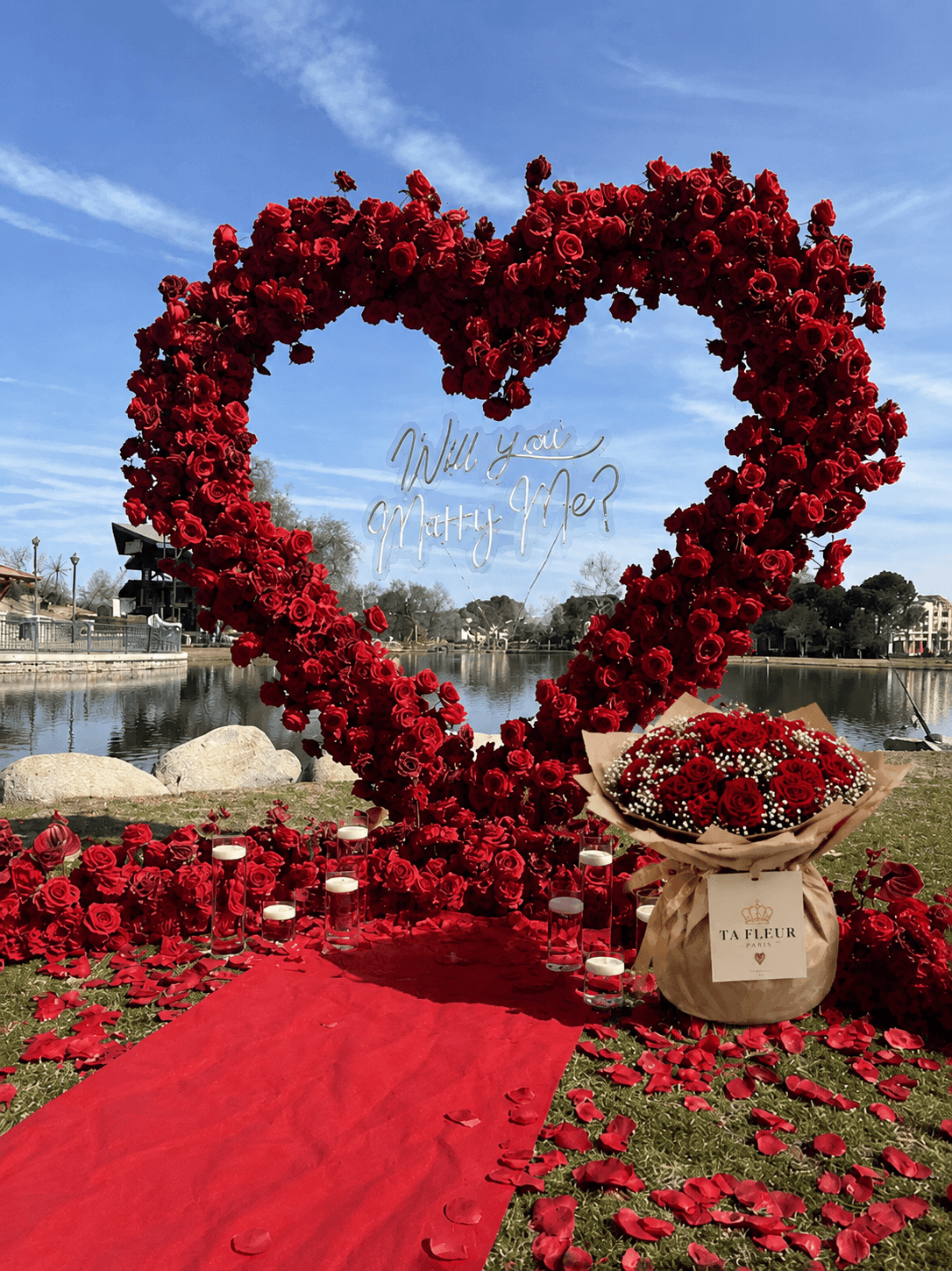 Arche de roses rouges Will You Marry Me avec bouquet TA FLEUR, tapis rouge et bougies au bord du lac