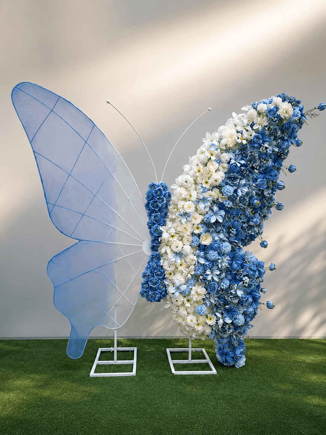 Sculpture papillon en roses bleues et blanches sur pelouse, décoration événementielle TA FLEUR